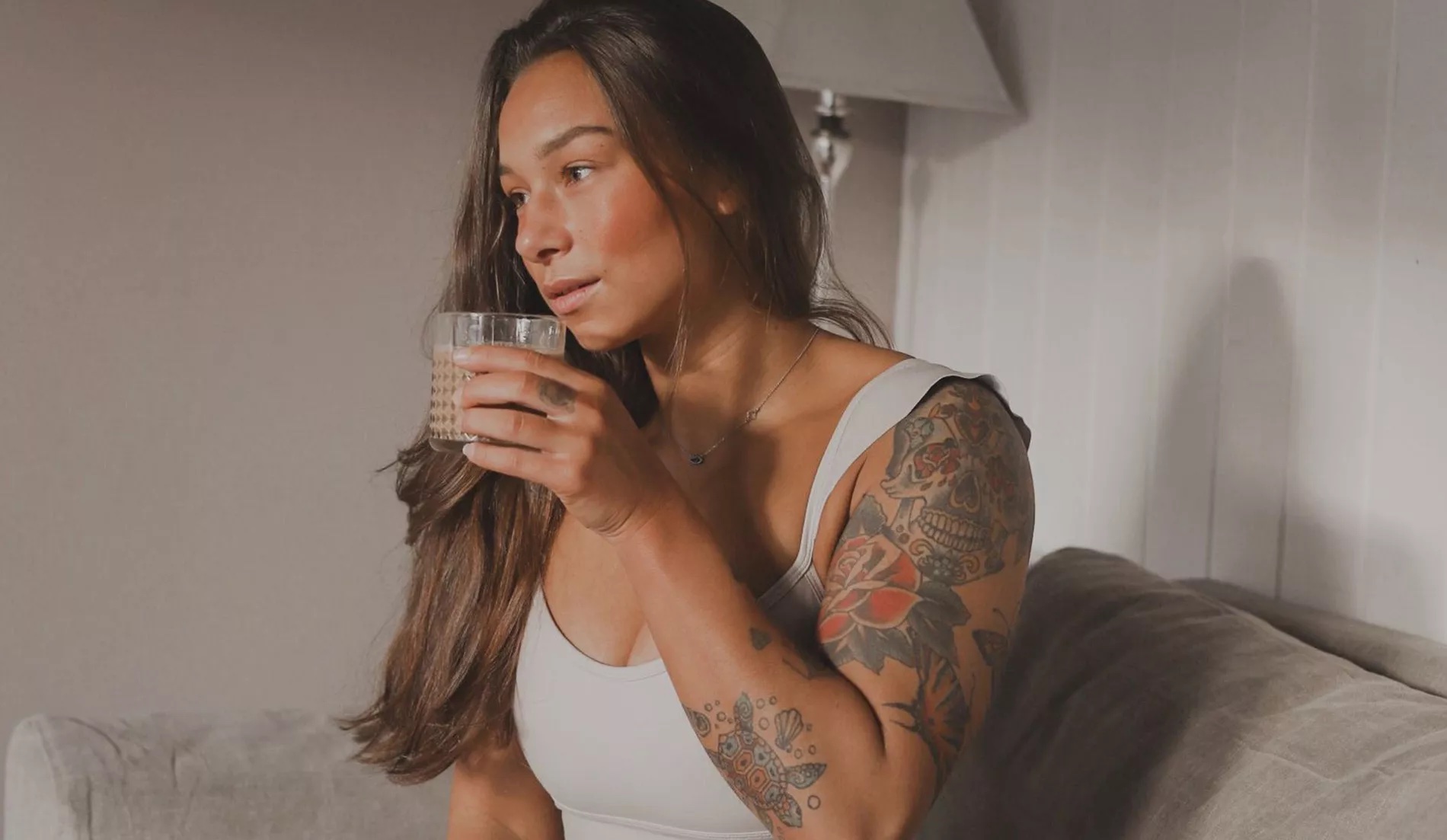 Gebräunte Frau mit einem Glas Wasser.